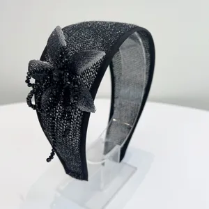 Macro detail of a handmade black beaded flower on a stylish glittery wide-brimmed headband