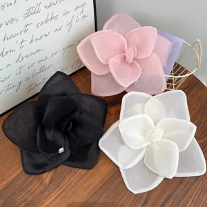 Close-up of three large mesh rose flower hair clips in pink, black, and white colors