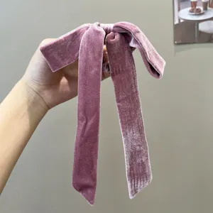 Detailed macro shot of an elegant pink velvet bow hair scrunchie with long ribbons