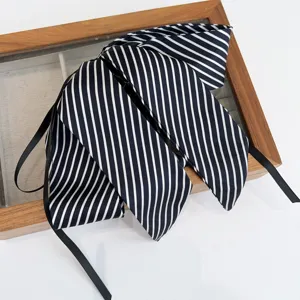 Nahaufnahme einer eleganten schwarz-weiß gestreiften Haarschleife auf einem Holztablett