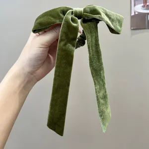 Detail of a green velvet bow hair tie with elegant long streamers for women's hair.