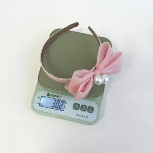 Detailansicht eines rosa Schleifen-Stirnbands mit Perlen, Gewicht 30,2 g auf einer Waage.