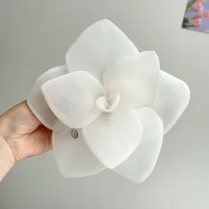Detailed view of the oversized white mesh rose flower hair clip with metal charm