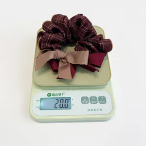 Detail view of a stylish plaid scrunchie with bow showing weight of 20.0g on a scale