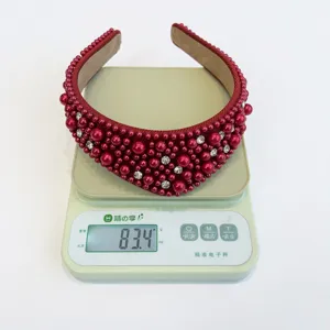 Dettaglio di un cerchietto imbottito rosso con perle e strass su una bilancia digitale