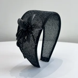 Close-up of a elegant black wide headband featuring handmade beaded flower detail.