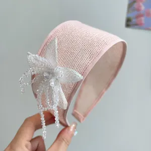 Close-up detail of a pink mesh wide headband with an elegant handmade beaded flower decoration.