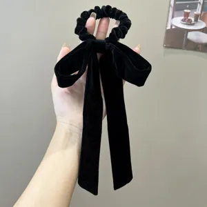 Detail view of this elegant black velvet bow scrunchie with soft long ribbon tails