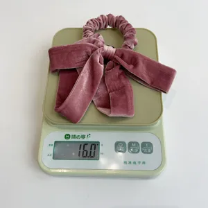 Mauve velvet bow hair scrunchie shown on a digital scale weighing exactly 16.0 grams.