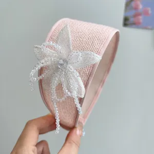 Close-up of a pink woven wide headband featuring a handmade beaded mesh flower detail