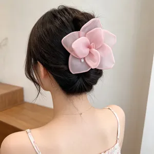 Elegant pink mesh rose hair claw clip shown in a romantic bun hairstyle detail