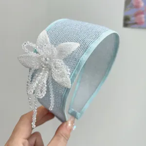 Close-up of elegant light blue wide headband with handmade beaded flower tassels