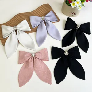 Close-up of five assorted satin and patterned bow hair clips featuring elegant camellia centers.