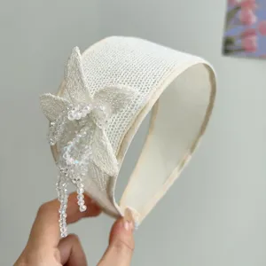 Detail view of handmade off-white beaded flower headband with elegant crystal tassel accents