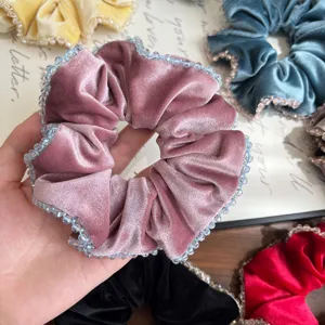 Nahaufnahme eines rosa Samt-Scrunchie mit Kristallperlen am Rand
