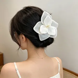 Detailed view of a large white mesh rose hair clip worn in a romantic updo hairstyle