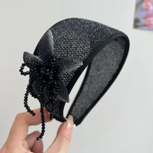 Close-up of handmade black beaded flower and tassel on a wide glitter headband