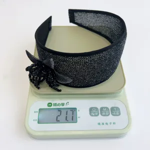 Black glitter wide headband with beaded flower on a scale showing 21.7g weight