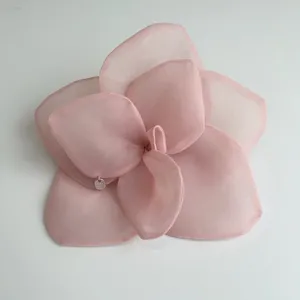 Macro detail of an oversized pink organza rose hair flower with small silver tag