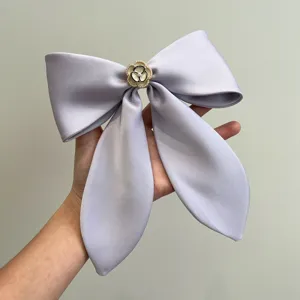 Close-up of large lilac satin bow hair clip with white camellia flower and pearl detail