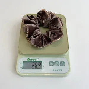 Nahaufnahme eines braunen Samthaargummis mit Kristallperlen, 26,9g auf einer Waage.