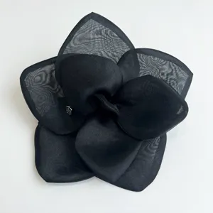 Close-up detail of oversized black mesh rose hair clip with elegant satin fabric petals