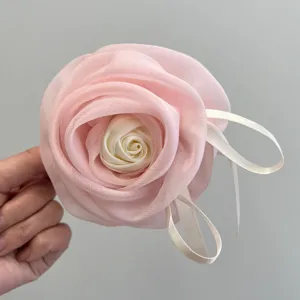 Primer plano detallado de una pinza para el pelo con una gran rosa de tela rosa