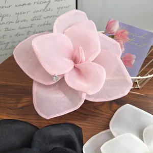 Detail shot of a large pink mesh rose hair clip with elegant layered organza petals.