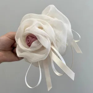 Primer plano de una pinza para el pelo con rosa de malla blanca y cintas blancas.
