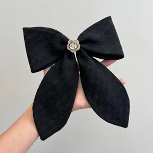 Close-up of a black lace bow hair clip featuring a vintage camellia flower center.
