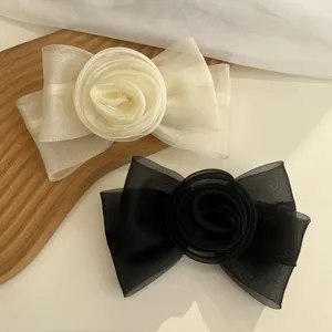 Gros plan sur d'élégantes barrettes à cheveux rose en résille noir et blanc crème.