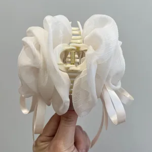 Detalle de una pinza para el pelo de rosa de malla crema grande sostenida por la mano