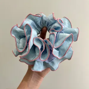 Vista detallada de un coletero de volantes azul claro de varias capas con bordes rosas