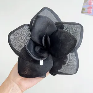 Macro detail of a large black mesh rose hair accessory showing intricate fabric layers