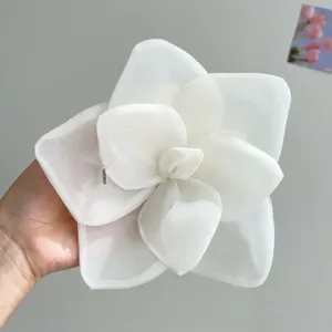 Detail showing the delicate texture of a large white mesh flower hair clip for women