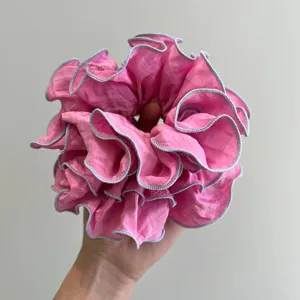 Primer plano de un coletero rosa grande con volantes y costuras de borde lavanda