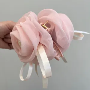 Primer plano de una pinza de pelo de rosa de gasa rosa con elegantes cintas blancas