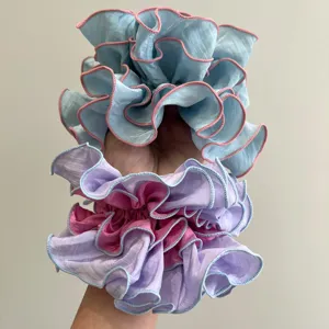 Coleteros fruncidos de varias capas en azul pastel y violeta con bordes contrastantes.