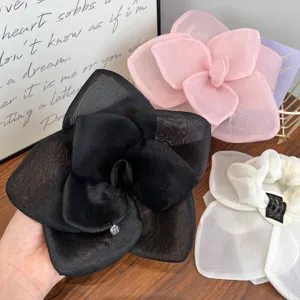 Close-up of oversized mesh flower hair clips in black, pink, and white organza