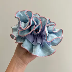 Detalle de cerca del coletero de organza plisado multicapa en azul y violeta claro.