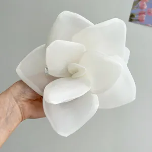 Macro detail of a large white mesh fabric rose hair clip with elegant layered petals.