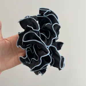 Detalle de coletero negro con volantes multicapa y bordes azul claro