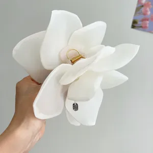 Close-up view of a romantic oversized white mesh rose flower hair claw clip for women