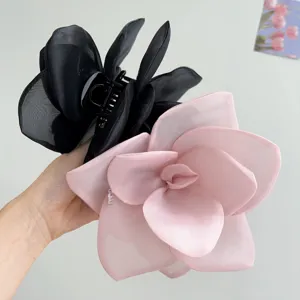 Close-up of elegant oversized mesh rose flower hair claws in black and soft pink colors