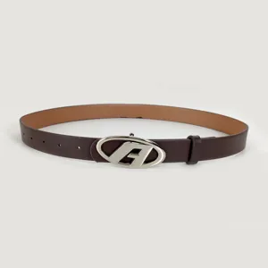 Closeup of brown leather belt with silver oval buckle, retro style accessory detail shot.