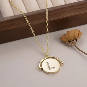 Gros plan macro d'un pendentif en or circulaire rotatif avec la lettre L sertie de cristaux fins