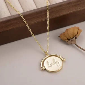 Vue macro d'un pendentif rotatif rond en or gravé 'lucky' sur une délicate chaîne en maille O.