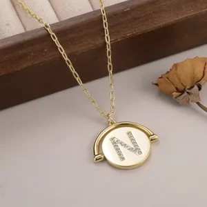 Détail rapproché d'un pendentif doré pivotant orné d'une lettre N sertie de strass