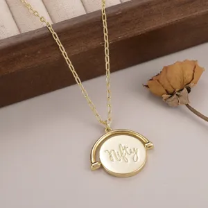 Vue détaillée d'un pendentif circulaire doré rotatif avec l'inscription Nifty