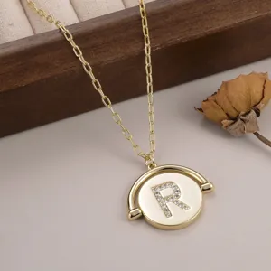 Vue détaillée d'un collier doré avec pendentif rond rotatif et lettre R en strass